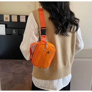 Detailed view of bright orange nylon crossbody bag with dual zippers and sturdy black buckle