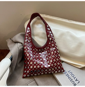 Détail du sac hobo bordeaux avec rivets argentés dans un décor de mode élégant