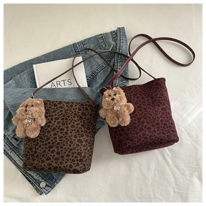 Detail of leopard print bucket bags in dark brown and red with plush bear charms