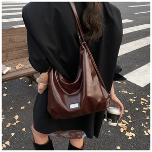 Deep brown glossy hobo bag shown on shoulder in stylish street photography