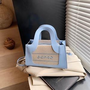 Blaue Umhängetasche mit beigem Kontrastfeld und BEPRO-Schriftzug auf einem Trenchcoat