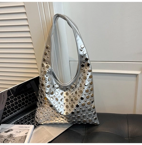 Détail du sac hobo argenté métallisé avec rivets ronds sur une surface sombre