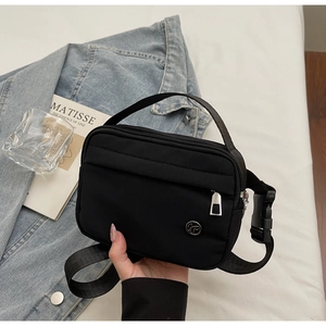 Detail of black nylon crossbody tote bag with adjustable strap and metal logo