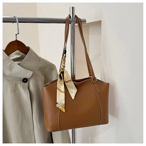 Brown leather tote bag featuring long straps and a decorative printed silk scarf detail