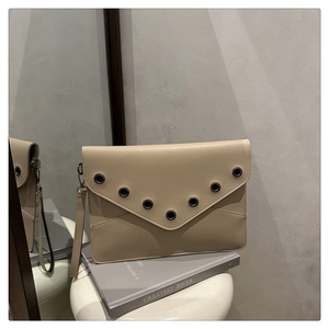 Detail der beigen Umschlag-Clutch mit Metallösen auf einer matten Leder-Oberfläche