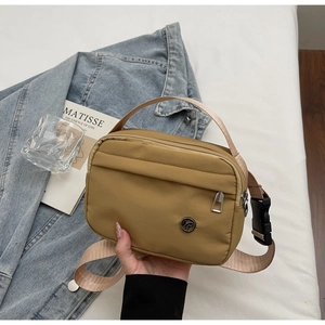 Detail of khaki nylon crossbody bag with adjustable strap and front zipper pocket