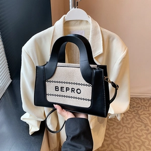 Detail van het BEPRO-logo op een tweekleurige canvas en zwart lederen tas