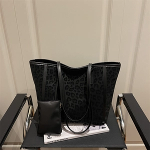Sac fourre-tout à motif léopard avec petite pochette sur une chaise en cuir noir