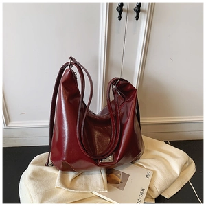 Detail of burgundy large tote bag with polished faux leather and metal logo plaque