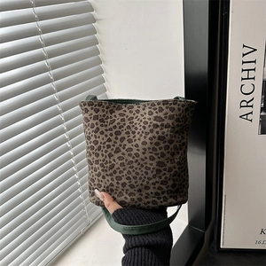 Large leopard print tote bag with dark green leather straps shown in lifestyle setting