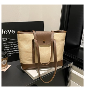 Close-up of contrast color canvas tote bag with brown leather trim and button detail