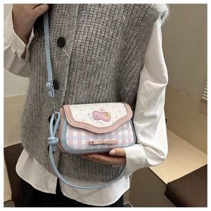 Close-up of pink and blue plaid crossbody bag featuring 3D bow and cherry print detail