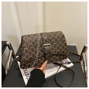 Detail of brown crossbody bag with M-letter monogram pattern and silver chain strap