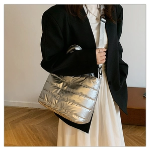 Détail d'un sac à bandoulière matelassé argenté avec une large sangle sur un modèle