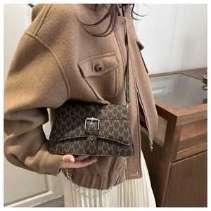 Detail of vintage brown shoulder bag with M-letter print and silver buckle detail