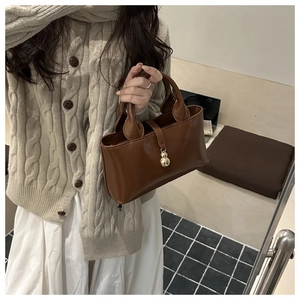 Dettaglio borsa tote marrone scuro con ciondolo metallico dorato a forma di zucca