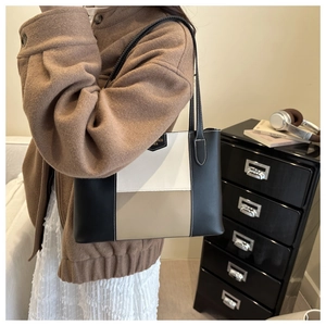 Detail of a three-color patchwork tote bag featuring leather straps and a golden metal logo