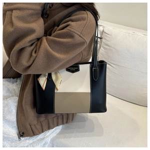 Detail of color-block tote bag featuring silk scarf accessory and metal leather brand tag