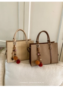 Straw tote bags with leather trim and tassel charms on a white sofa in a minimalist setting