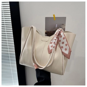 Close-up of cream PU leather tote bag with a pink polka dot silk scarf tied to the handle