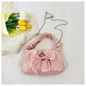 Détail du sac à main rose à nœud avec poignée froncée et élégante chaîne argentée