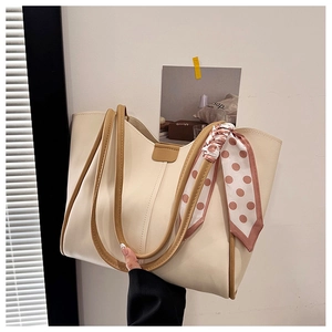 Detail of a large cream tote bag with stylish polka dot scarf and brown leather handles