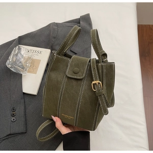 Detail of army green bucket bag with white contrast stitching and gold buckle strap