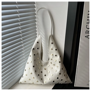 Close-up of white leather underarm bag with gold studs on a sunlit window sill