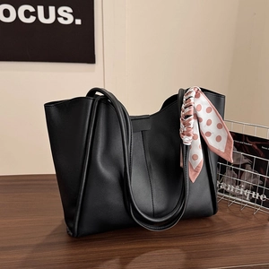 Large black leather tote bag with elegant polka dot silk scarf handle on wooden surface