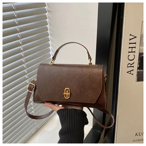 Detail of vintage dark brown handbag with wax leather texture and gold twist lock