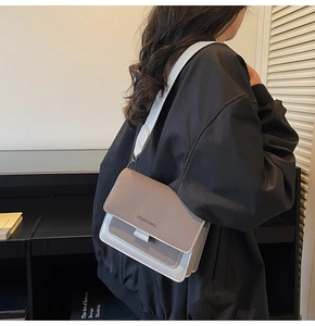 Detail view of contrast color crossbody bag with wide strap and embossed fashion text