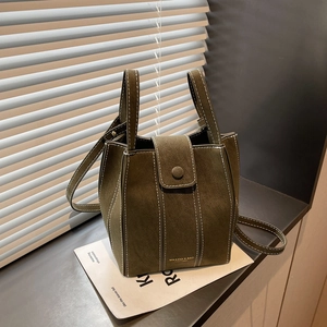 Green suede bucket bag with white contrast stitching and adjustable shoulder strap