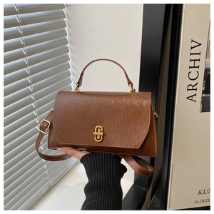 Detail of vintage brown textured leather crossbody bag with golden twist-lock and hand hold