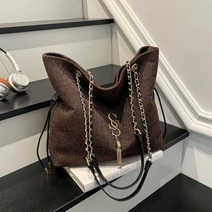 Borsa tote marrone con paillettes, catena dorata e frange su una scala moderna