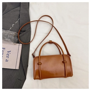 Detail of a brown leather crossbody bag featuring the embossed FASHION text and knot handles