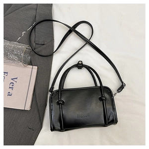 Flat lay of black glossy rectangle bag with FASHION text and adjustable strap