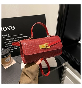 Dettaglio borsa rossa intrecciata con chiusura dorata e manico superiore elegante