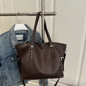 Dark brown tote bag with silver star rivets and shoulder strap in a minimalist setting