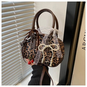 Close-up of leopard print Boston bag with heart charms, pearls, and cherry pendants