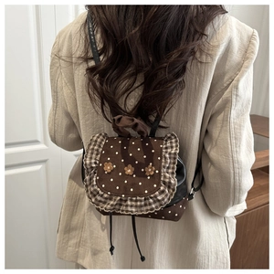 Detail of a brown polka dot mini backpack featuring floral accents and checkered ruffles
