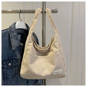 Detail of cream corduroy tote bag with vertical stripes and FASHION leather label