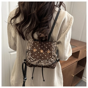 Close-up of mini backpack with brown polka dot fabric and floral ruffles