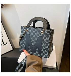 Close-up of charcoal grey crossbody bag with M logo pattern and golden metal hardware
