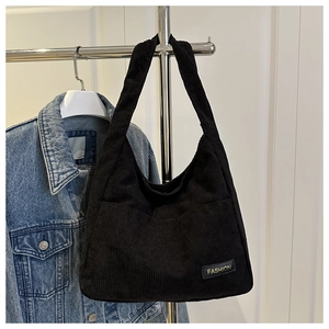 Detail of black corduroy tote bag showing vertical texture and FASHION label