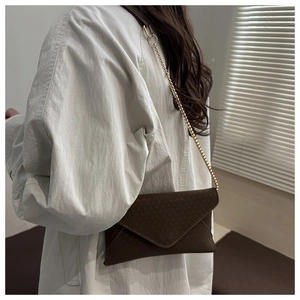 Brown frosted leather envelope bag with gold chain strap shown on model's shoulder