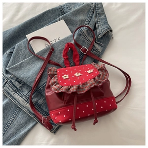Detail of red floral backpack with polka dots, drawstring closure and ruffled edges