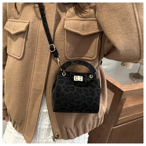 Detail of leopard print suede handbag featuring golden twist lock and adjustable shoulder strap