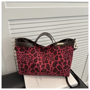 Detail of red leopard rose tote bag with brown leather straps and gold metal logo
