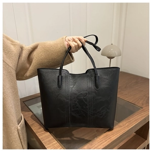 Detail of a black large tote bag with vertical stitching and matte leather texture