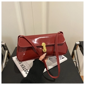 Détail du sac bandoulière en cuir verni bordeaux avec un fermoir doré brillant